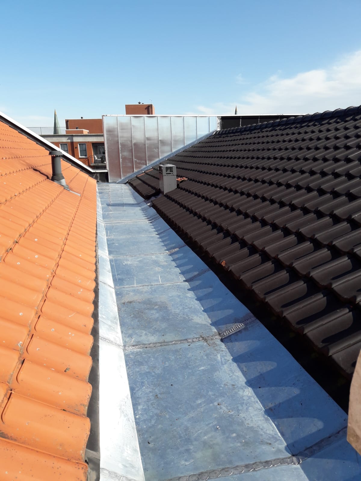Zinken kilgoot tussen een oranje en een antraciet pannendak