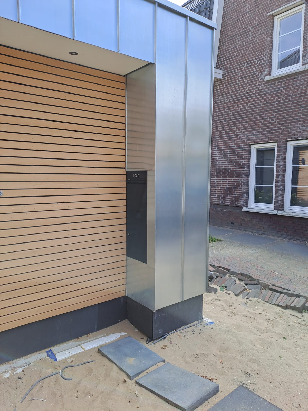 Zinken bekleding rond een entree met brievenbus